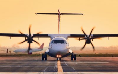 Front view of propeller airplane taxiing to runway for take off. Traffic at airpot at sunset.