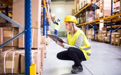 Young woman worker or supervisor with clipboard. Warehouse workers controlling stock.